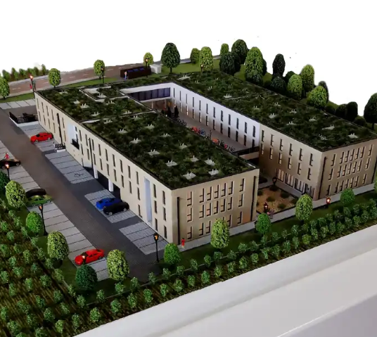 Une scène d’exposition pour la Vienna Design Week avec une maquette d’architecture éclairée et animée signée ARI Maquette : îlot mixte orienté innovation, places de recharge EV, routes de navettes autonomes, phases modulaires de construction et espac